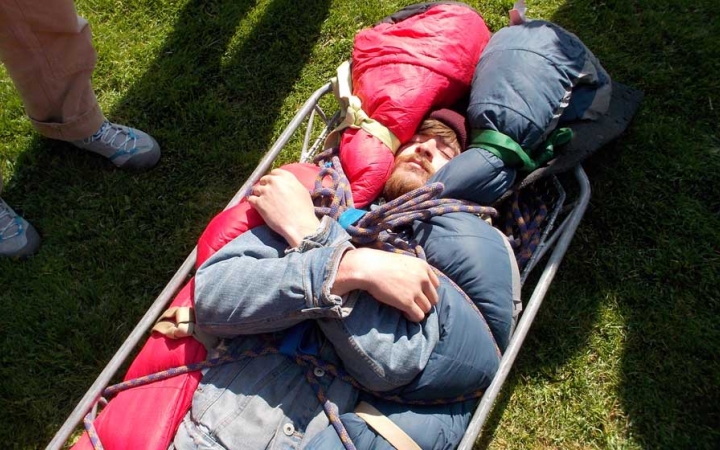 A person lays bundled in a stretcher during a wilderness first responder course